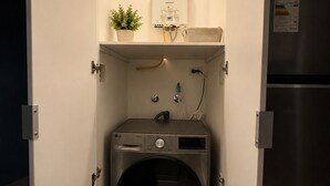 A compact laundry room with a front-loading washer, a water heater, and a refrigerator.