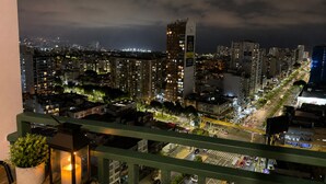 A nighttime cityscape with illuminated buildings, a prominent tower, and a busy street.