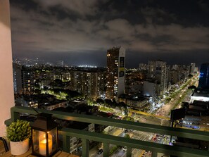A nighttime cityscape with illuminated buildings, a prominent tower, and a busy street.