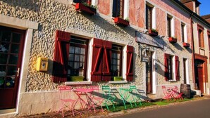 A building with a stone facade, red shutters, and outdoor seating. - Immerse yourself in this spacious 26m² room inspired by the mastery of light. (Giverny)