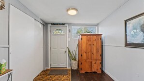A hallway with a wooden floor, a white door, a wooden cabinet, and a framed picture on the wall. - Beach Cottage w Hot Tub & Screened Porch! (Old Orchard Beach)