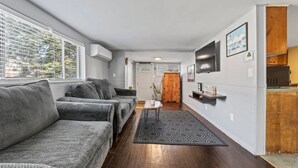 A modern living room with a sofa, a coffee table, and a TV mounted on the wall. - Beach Cottage w Hot Tub & Screened Porch! (Old Orchard Beach)