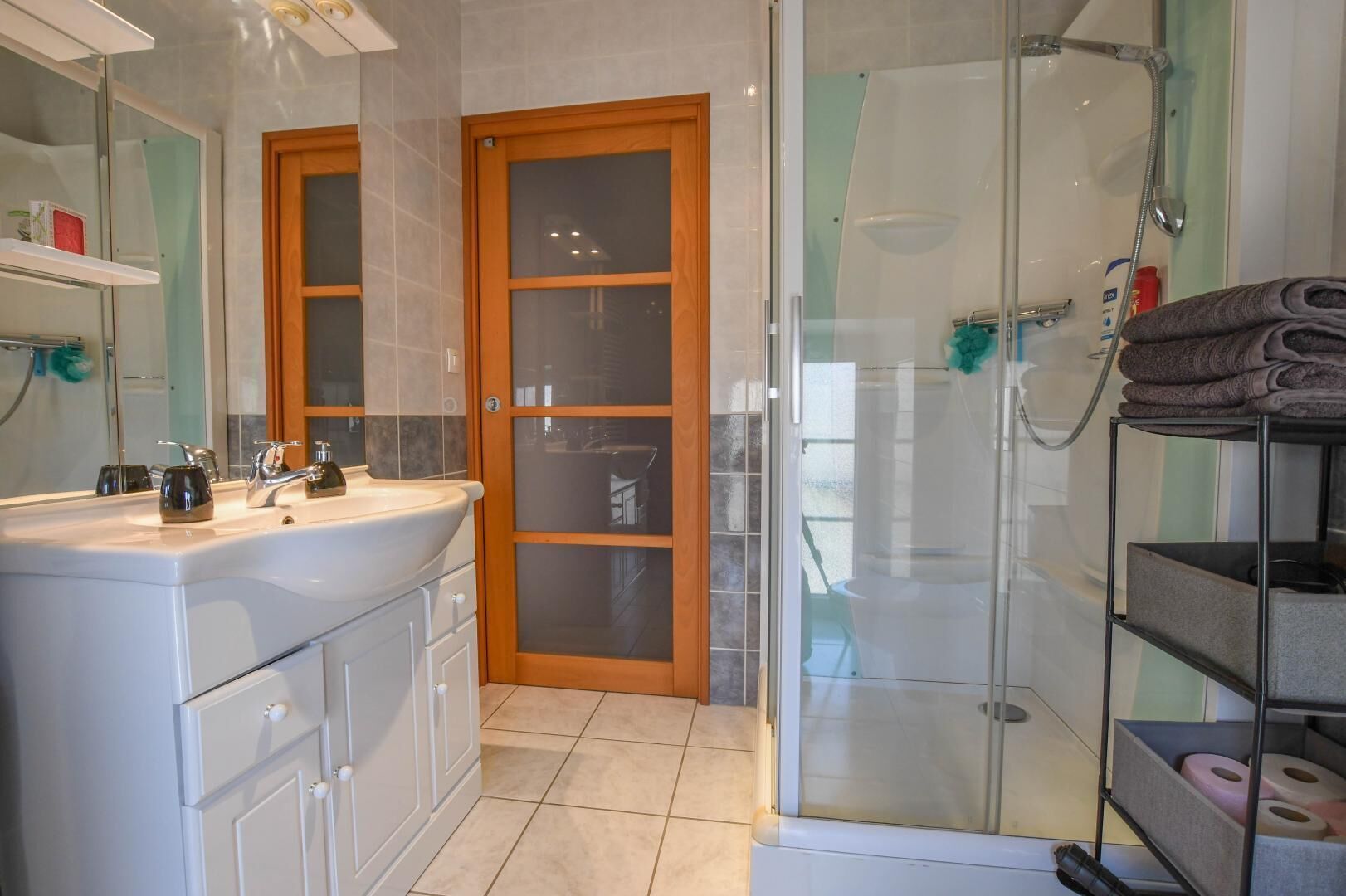Une salle de bain équipée d’un lavabo, d’un miroir, d’une douche et d’une porte en verre.
