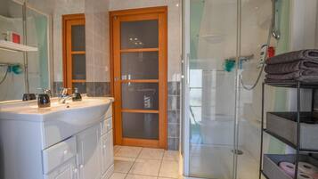 Une salle de bain équipée d’un lavabo, d’un miroir, d’une douche et d’une porte en verre.