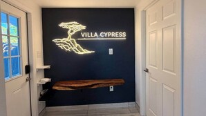 Un pasillo con un letrero de neón que dice 'VILLA CYPRESS' y una estantería de madera.