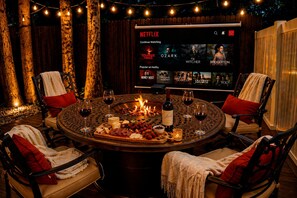 A cozy outdoor seating area with a fire pit, wine glasses, and a Netflix display. - Minutes to AMI • Fire Pit + Outdoor Movies (Bradenton)
