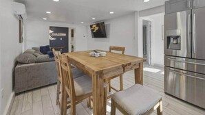 Una cocina moderna con una mesa de comedor de madera, electrodomésticos de acero inoxidable y un sofá gris.