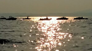 A calm body of water with boats and a distant shoreline. - At Lake Garda in the greenery and tranquility. (Veneto)