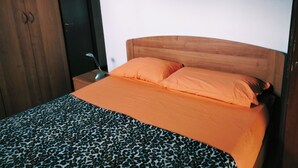 A bedroom with a bed, a nightstand, a lamp, and a wardrobe. - At Lake Garda in the greenery and tranquility. (Veneto)
