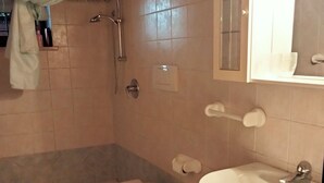 A bathroom with two toilets, a sink, a shower, and a towel rack. - At Lake Garda in the greenery and tranquility. (Veneto)