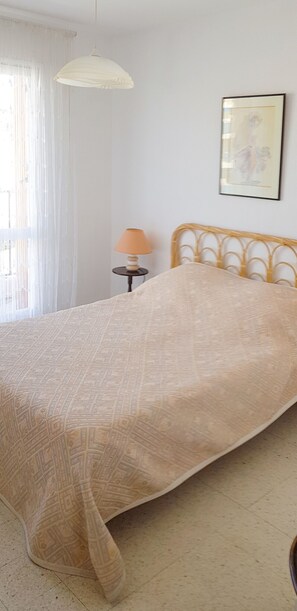 A bed with a patterned bedspread, a bedside lamp, and a framed picture on the wall. - Golfe Juan charmant appartement garage proche mer (Vallauris)