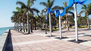 A seaside promenade with palm trees, benches, and a tiled walkway. - Treasure Coast Hideaway | Dogs Welcome, No Fees (Fort Pierce)