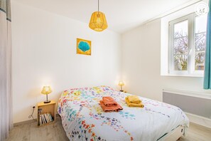 A bedroom with a floral bedspread, two bedside lamps, a window with curtains, and a small bedside table with books. - Pâtis Karadok - MESVRES (MESVRES)
