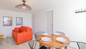 Un salon moderne avec une table à manger pour quatre personnes, un canapé et un luminaire suspendu au plafond.