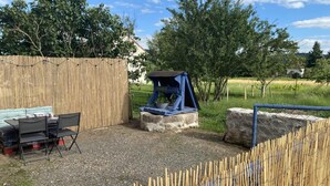 Un jardin avec une clôture en bois, une structure de jeu bleue et une table avec des chaises.