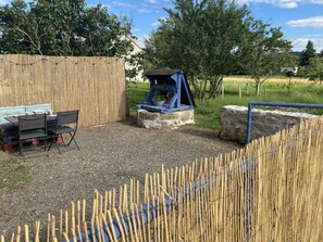 A backyard with a wooden fence, a blue play structure, and a table with chairs. - Pâtis Karadok - MESVRES (MESVRES)