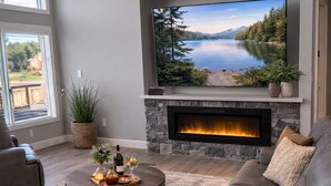 Een moderne woonkamer met een open haard, een grote flatscreen-tv, leren banken en een ronde salontafel.