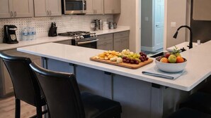 Een moderne keuken met een centraal eiland, barkrukken, een magnetron en een fornuis.