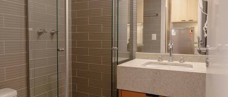 A modern bathroom with a glass-enclosed shower, a sink with a mirror, and a toilet.