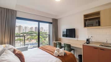 Habitación de hotel con cama, escritorio, televisor y vistas a la ciudad.