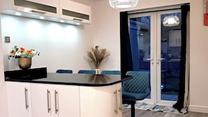 A modern kitchen with white cabinets, a black countertop, and a pendant light. - 2 Bed Home - Parking, Private Garden, Wifi (Derby)