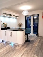 A modern kitchen with white cabinets, a black countertop, and a pendant light.