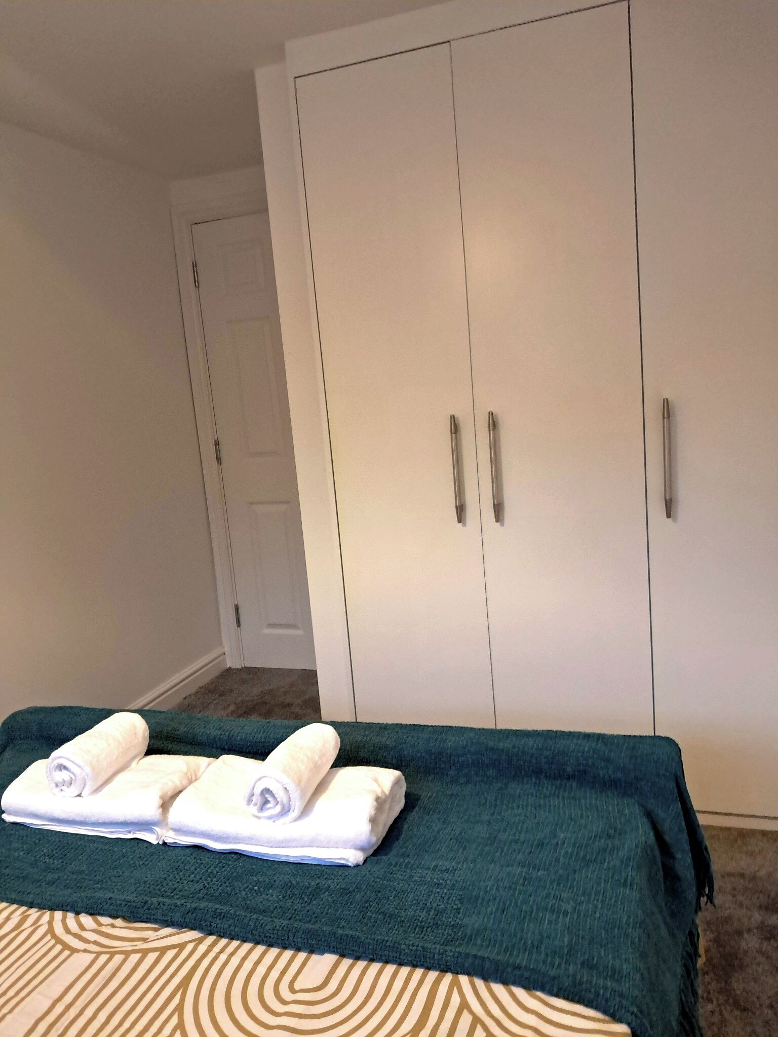 Ein Schlafzimmer mit einem Bett, einer grünen Decke und weißen Kleiderschränken.