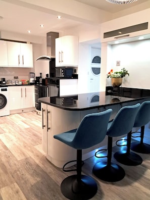 Una cocina moderna con una isla central, taburetes de bar y una lavadora.