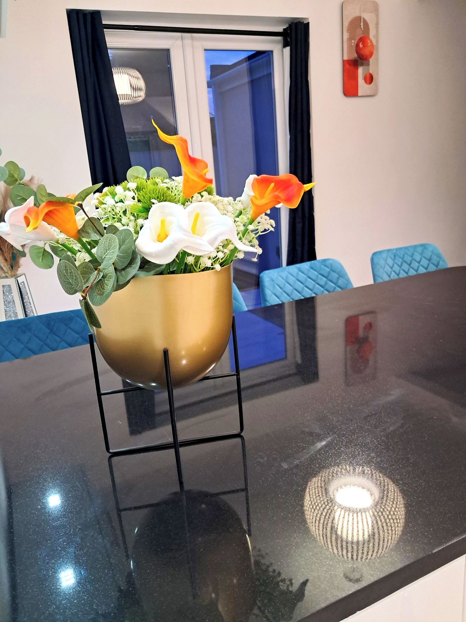 Une pièce comprenant une table, des chaises, une fenêtre avec des rideaux et un détecteur d’incendie fixé au mur.