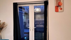 A living room with a blue sofa, a hanging light fixture, and a sliding glass door leading outside. - 2 Bed Home - Parking, Private Garden, Wifi (Derby)
