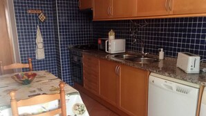 Una cocina con mesa, sillas, microondas, tostadora y lavavajillas.