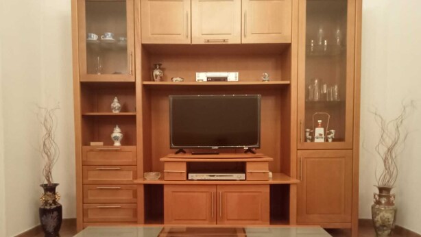 Un mueble de entretenimiento de madera con televisor de pantalla plana, estanterías integradas y armarios.