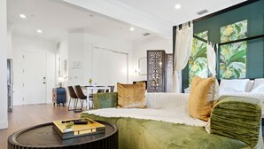 Ein modernes Wohnzimmer mit einem grünen Sofa, einem runden Couchtisch und einem Essbereich im Hintergrund.