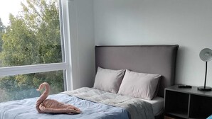 A bedroom with a bed, a nightstand, a lamp, and a window. - Comfortable apartment in isla teja sector (Valdivia)