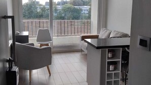 A modern apartment with a balcony, a sofa, a dining table, and a TV. - Comfortable apartment in isla teja sector (Valdivia)