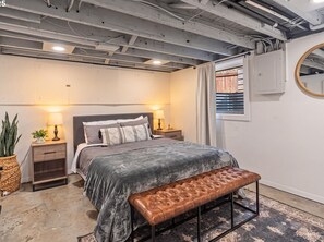 A bedroom with a bed, bedside tables, a bench, a potted plant, and a window with curtains. - Mississippi Ave Home - Walk to Dining,Shops,Music (Portland)