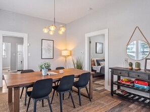 A modern dining area with a wooden table, black chairs, and a hanging light fixture. - Mississippi Ave Home - Walk to Dining,Shops,Music (Portland)