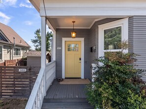 A residential house with a yellow front door, a porch with a white railing, and a mailbox. - Mississippi Ave Home - Walk to Dining,Shops,Music (Portland)