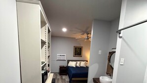 A narrow hallway leading to a bedroom with a bed, bedside table, and a small window. - Germantown Inn & Lounge (Hermann)