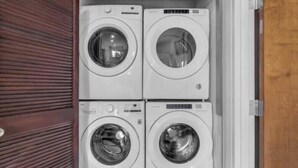 A laundry room with four stacked washing machines. - Germantown Inn & Lounge (Hermann)