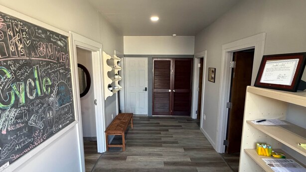 A hallway with a chalkboard, a bench, a colorful rug, and shelves with papers. - Germantown Inn & Lounge (Hermann)