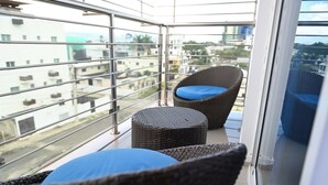 A balcony with wicker furniture, a metal railing, and a view of buildings. - Spacious 3-bedroom apartment in serene Santiago de los Caballeros with AC (Santiago de los Caballeros)