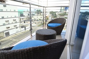 Ein Balkon mit Korbmöbeln, einem Metallgeländer und Blick auf Gebäude.