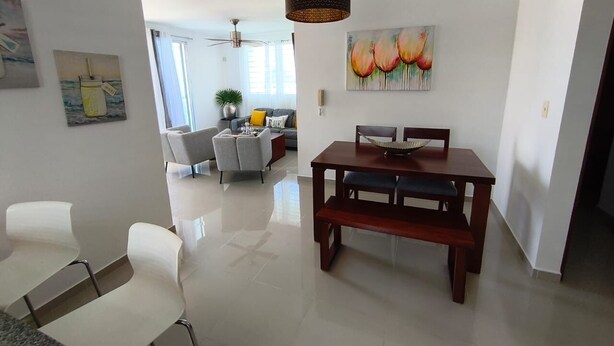 A modern living room with a dining area, a ceiling fan, and artwork on the walls. - Spacious 3-bedroom apartment in serene Santiago de los Caballeros with AC (Santiago de los Caballeros)