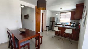 A modern kitchen with a dining area, wooden cabinets, and a stainless steel refrigerator. - Spacious 3-bedroom apartment in serene Santiago de los Caballeros with AC (Santiago de los Caballeros)