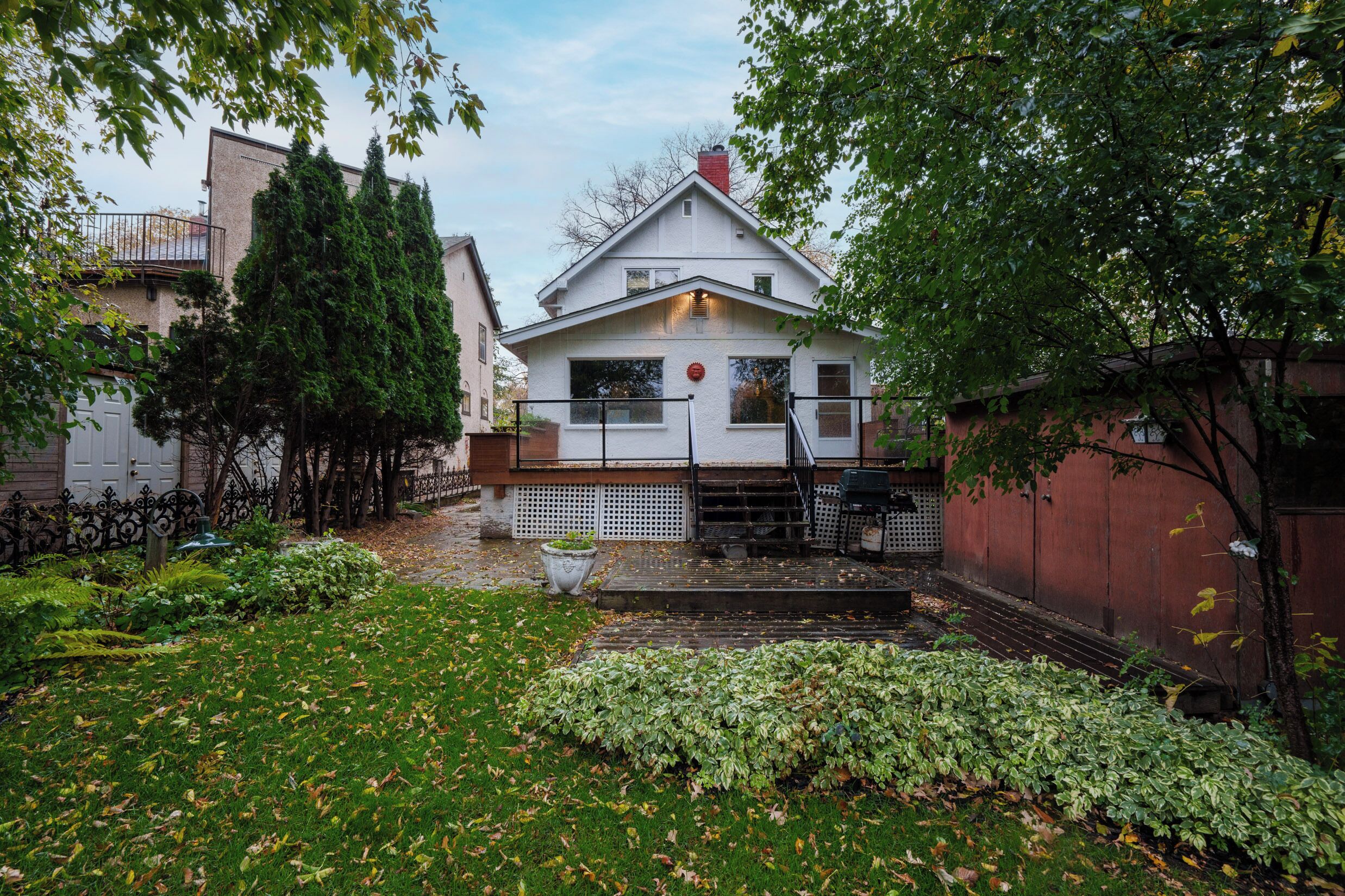 Una casa con facciata bianca, tetto rosso e un piccolo giardino con un vialetto che conduce all'ingresso.