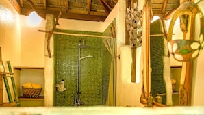 A bathroom with a green mosaic wall, a shower, a wooden ceiling, and a mirror with a decorative frame. - Charming 1BR Garden Bungalow (Temae)