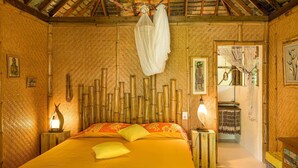 A room with a bed, bamboo wall decor, and a canopy. - Charming 1BR Garden Bungalow (Temae)