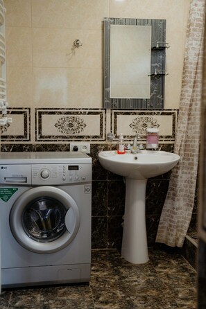 Un espace buanderie équipé d’un lave-linge et d’un évier.