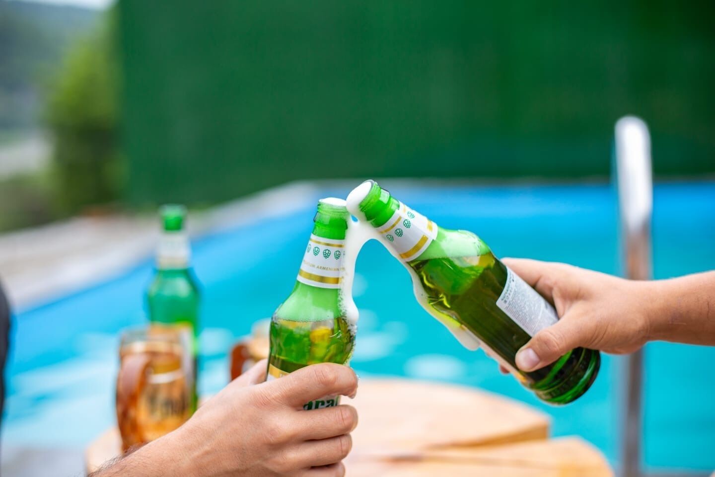 Een zwembadlandschap, waarbij iemand een drankje inschenkt uit een groene fles.